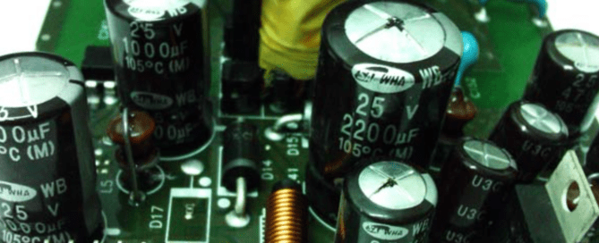 Fotografía comparativa mostrando un condensador electrolítico nuevo con tapa plana junto a un condensador electrolítico hinchado/inflado defectuoso con abultamiento evidente en la tapa superior