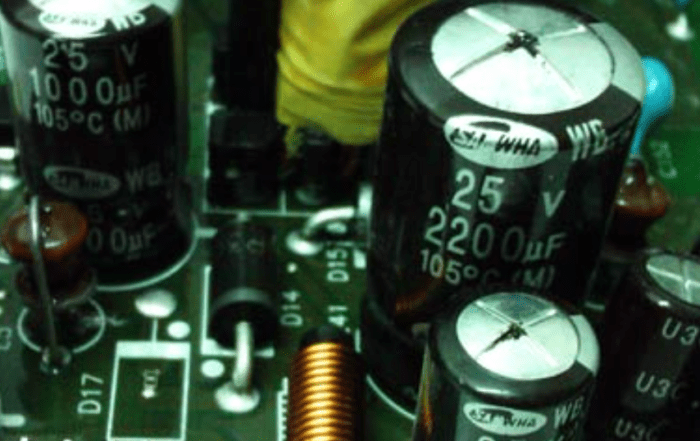 Fotografía comparativa mostrando un condensador electrolítico nuevo con tapa plana junto a un condensador electrolítico hinchado/inflado defectuoso con abultamiento evidente en la tapa superior