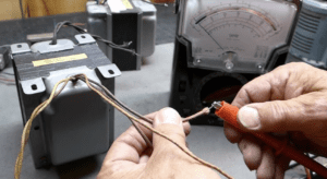 Guía del transformador de salida: El corazón del sonido a válvulas 3 Técnico profesional diagnosticando transformador de salida OT con multímetro en amplificador válvulas